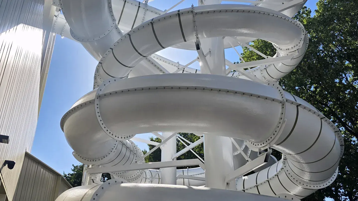 Witte spiraalglijbanen aan de buitengevel van een zwembad, gebouwd door AVASTO Recreatietechniek