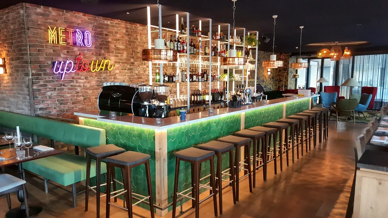 Bar met stalen achterwand, verlichte flessenschappen en neonletters in Metro City Kitchen in Utrecht