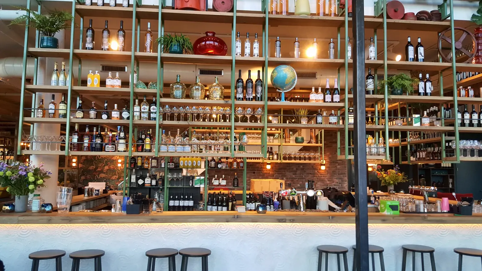 Groene stalen flessenwand in Metro City Kitchen in Utrecht