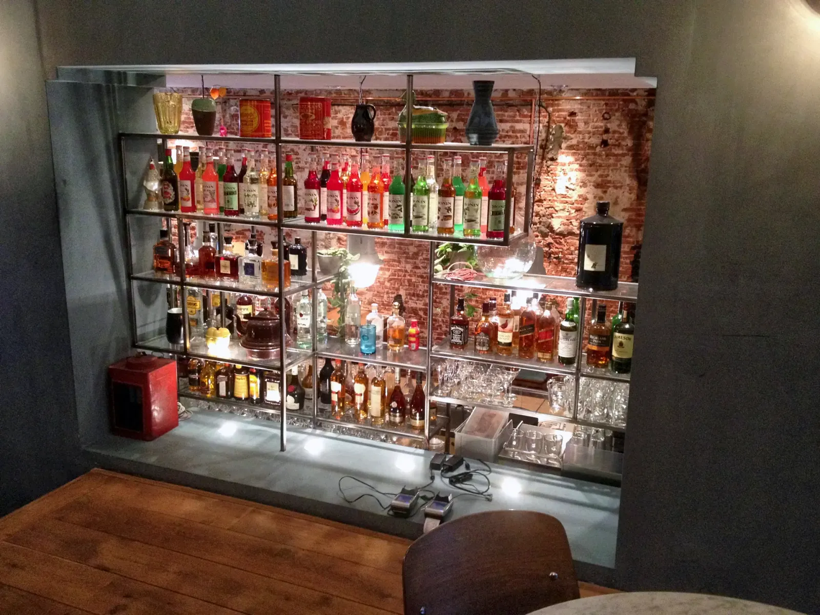 Stalen flessenwand met glazen schappen in restaurant Raak in Utrecht