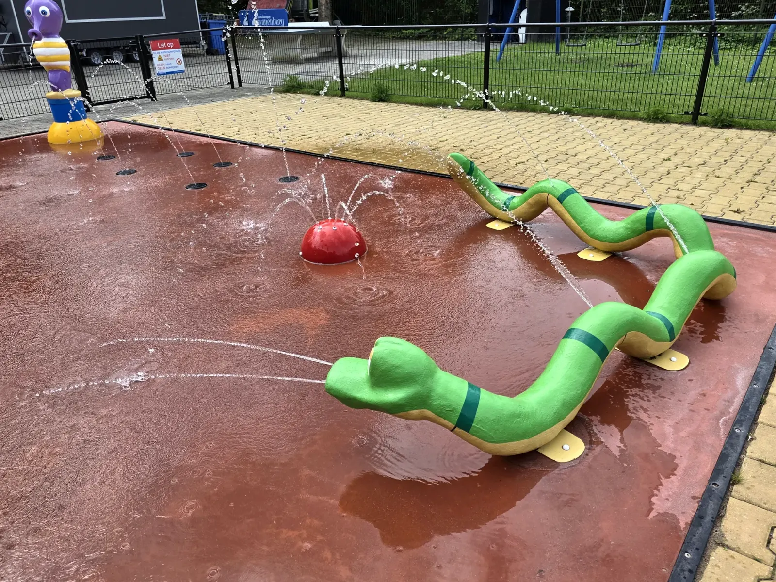 Groene slang-sproeier op het spraypark van Speeltuin Zwanenburg