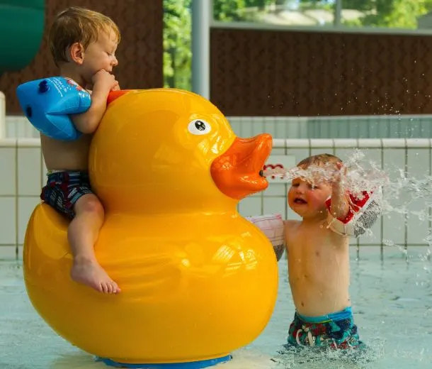 Kinderen spelen op een badeend-dierfiguur in een peuterbad